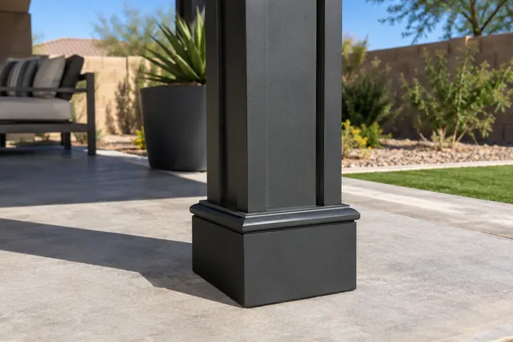 Base of a powder-coated aluminum pergola post with a decorative trim cover on a concrete patio, close-up