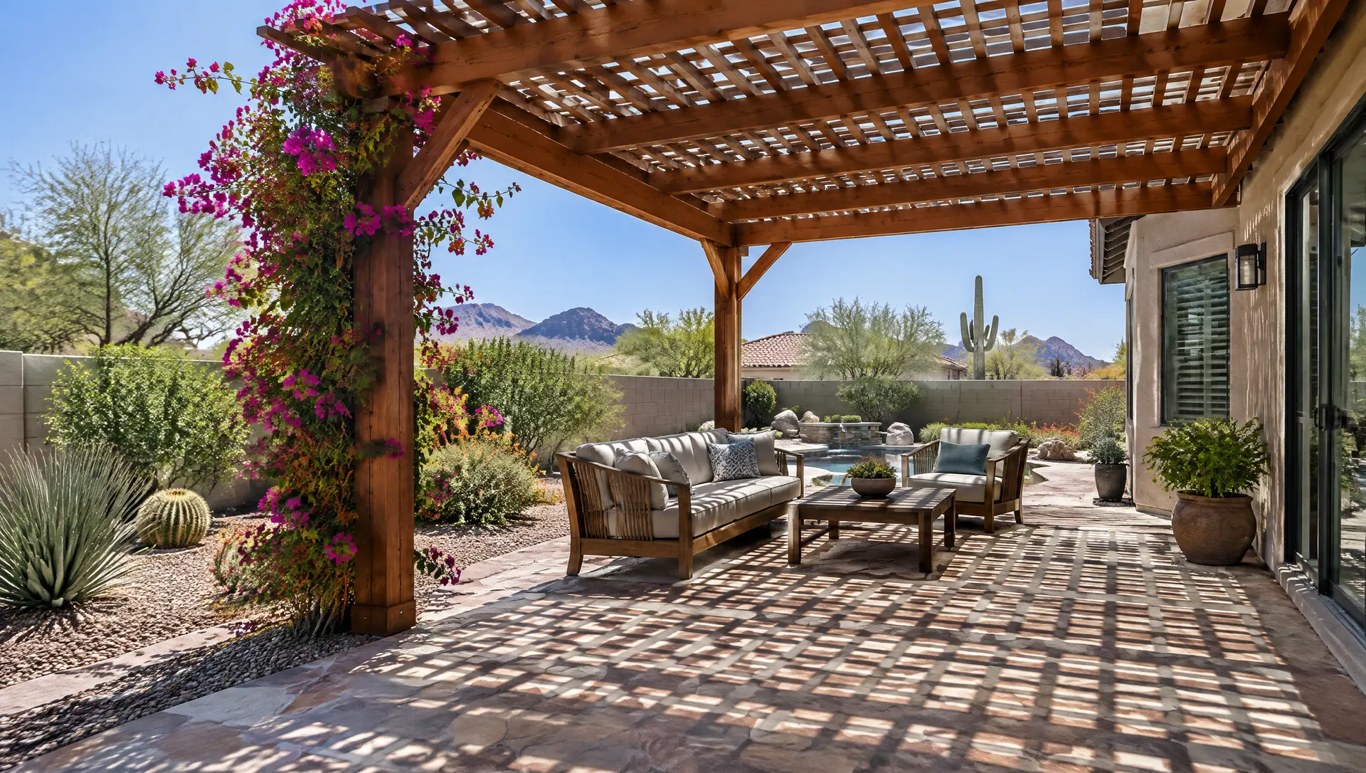 Warm stained wood pergola with a lattice-style rafter roof over a flagstone patio in a Phoenix backyard, bougainvillea starting to climb one post, crisp lattice shadows on the ground